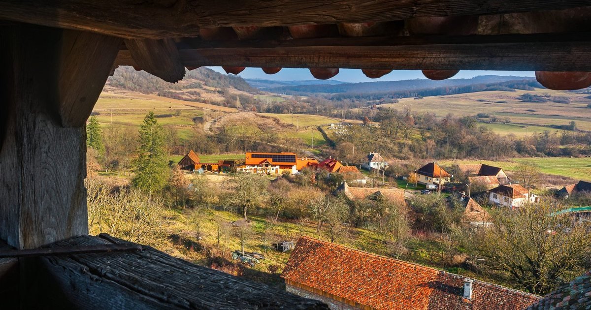 Șomartin from a barn window: the farm's orange roof among the trees.